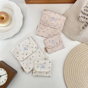 Close-up of floral fabric pouches with secure snap button and woven brand label