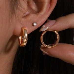 Orecchini a cerchio in oro lucido dal design minimalista indossati da una modella donna