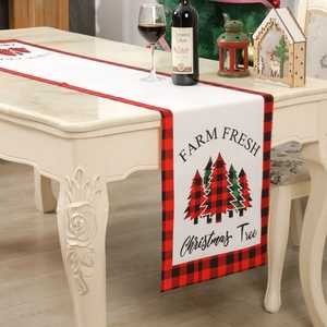 Christmas tree table runner with red and black plaid borders on a festive white table