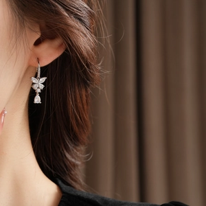 Gros plan d'une boucle d'oreille papillon en zircon avec pendentif goutte sur modèle