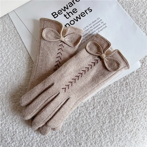 Detailaufnahme der beigen Wollhandschuhe mit eleganter Schleife und Weizenstickerei