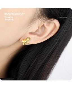 Detail view of irregular lava texture gold stud earrings shown on a model's ear