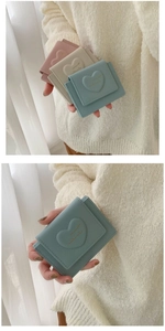 Detailed view of macaron colored heart embossed faux leather tri-fold wallets in pastel shades