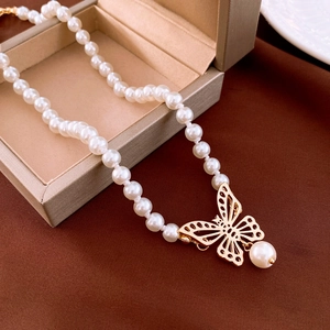 Gros plan détaillé du collier de perles avec pendentif papillon doré sur tissu velours