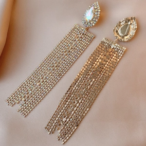 Macro shot of gold teardrop earrings with dense sparkling rhinestone fringes on satin