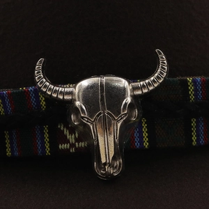 Detailed macro view of vintage silver bull skull ornament on felt cowboy hat with woven band