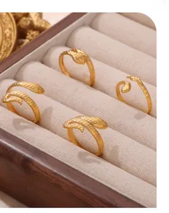 Macro detail of gold plated snake rings with intricate scale patterns on beige velvet
