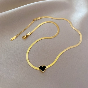 Macro detail of gold herringbone chain with black heart pendant and S925 engraving