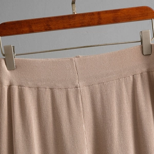 Detail of high-waist knit pants with elastic waistband and vertical striped texture