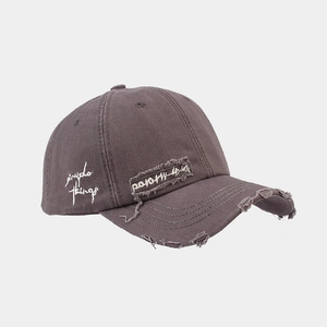 Close-up of distressed grey cotton baseball cap featuring embroidered psycho things text