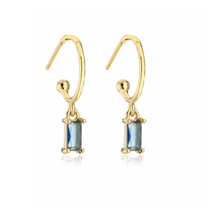 Detail of gold-plated earrings with rectangular blue zircon pendant on white background