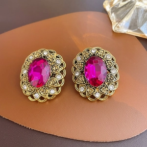 Close-up of vintage gold floral earrings with rose red stones on leather background