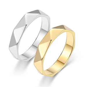 Dettaglio di anelli geometrici sfaccettati in oro e argento per coppie alla moda.