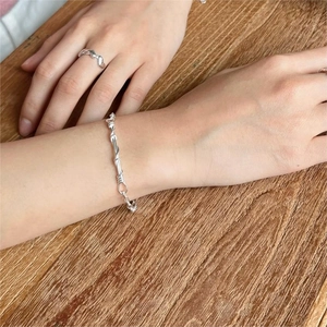 Detailed view of handmade twisted S925 sterling silver bracelet and ring on a person's wrist