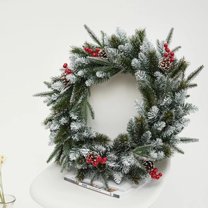 Premium Christmas wreath with PE pine needles, red berries, and snow flocking on a white chair