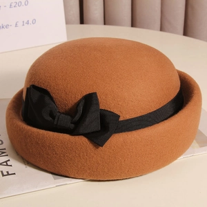 Dettaglio di un cappello cloche in lana cammello con fiocco in gros-grain nero