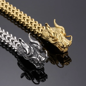 Gros plan de bracelets tête de dragon or et argent sur fond noir avec reflet miroir