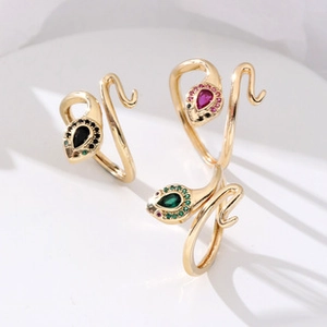 Detail view of brass snake rings with colorful crystal heads and adjustable gold band