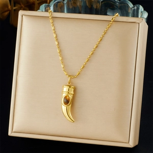 Detalle de collar con colgante de cuerno dorado y piedra ojo de tigre marrón en joyero