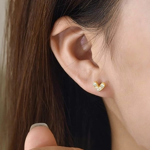 Detail of heart stud earrings with white micro-inlaid zircons on gold-plated metal