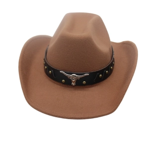 Detail of a brown felt cowboy hat featuring a leather band and silver bull head emblem