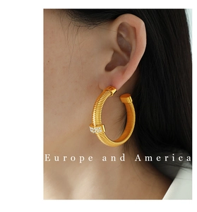 Close-up of gold hoop earrings with thread texture and sparkling rhinestones on model