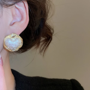 Primo piano di orecchini a cuore placcati in oro 16K con texture perlata su una modella