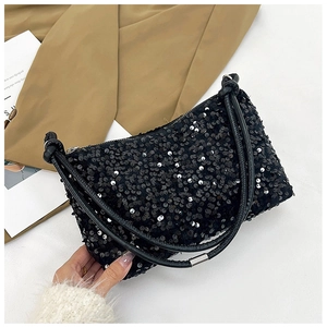 Detail of a chic black sequined baguette bag featuring a leather knotted handle and zipper
