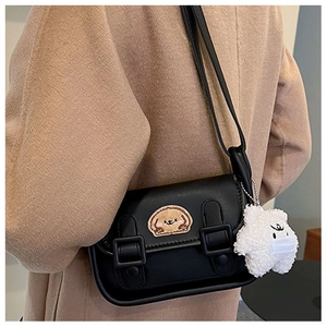 Detail of black crossbody bag with dog embroidery and plush bear charm on wool coat