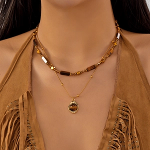 Close-up of a double-layered golden necklace with natural tiger eye beads on a model