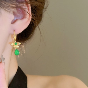Detail of vintage flower earrings with green resin teardrop and gold-plated floral hook