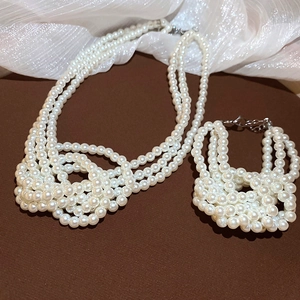 Detail of French three-layer knotted pearl necklace and bracelet jewelry set on fabric