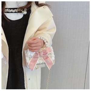 Detail of pink tweed girl's handbag with large bow, rose detail and pearl top handle