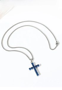 Detailed macro view of silver titanium steel cross necklace with blue zircon inlay