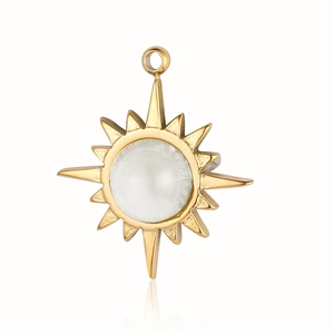 Dettaglio di un ciondolo a forma di sole dorato con perla bianca su sfondo bianco puro