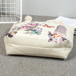 Detail view of beige canvas tote bag with floral elephant print and woven rope handles