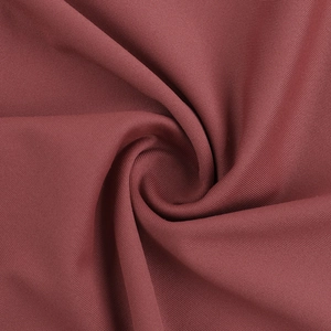 Gros plan sur le tissu élastique rouge foncé avec des plis en spirale et texture fine