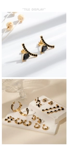 Détail de boucles d'oreilles en acier doré avec pierres noires et motifs de l'œil maléfique