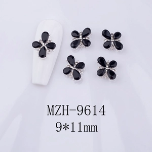 Detailed macro view of 9x11mm black floral nail art charm with zircon center on nails
