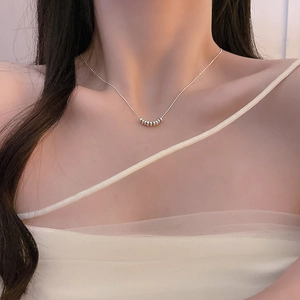 Close-up of minimalist silver snake bone chain necklace with small circular link details