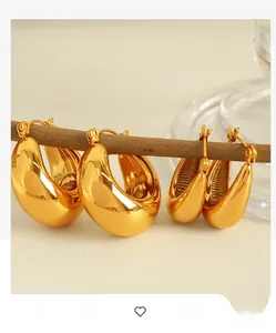 Polished 18K gold-plated chunky hoop earrings in two sizes hanging on a wooden display