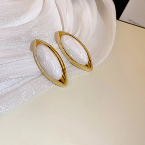 Dettaglio di orecchini vintage dorati con inserto in perla bianca su tessuto