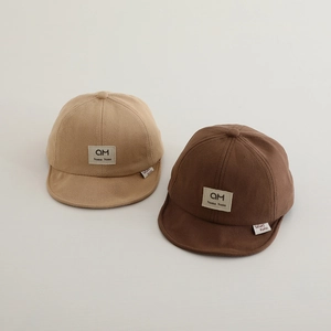 Detailed view of baby cotton baseball caps in brown and beige with soft brims and logo patches