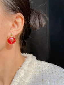 Close-up of vintage red round drop earrings with gold edges and green stone accent