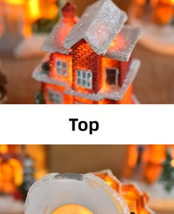 Close-up of lighted Christmas resin house with snowy roof and warm glowing LED windows