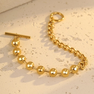 Golden bead and link chain bracelet with OT toggle clasp on a natural stone surface