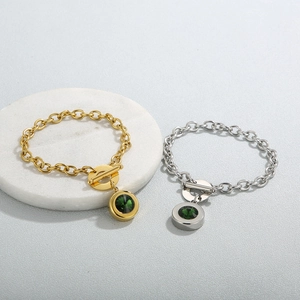 Macro detail of OT buckle stainless steel bracelets with green faceted stone charms