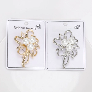 Detailed macro view of gold and silver pearl flower brooches on a white display card