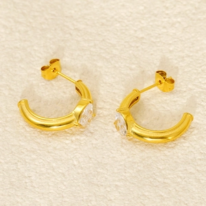 Detail of 18k gold plated C-shaped earrings with oval cubic zirconia setting
