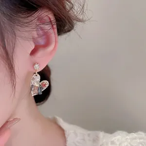 Elegant multi-color heart stud earrings with sparkling crystals worn on ear model
